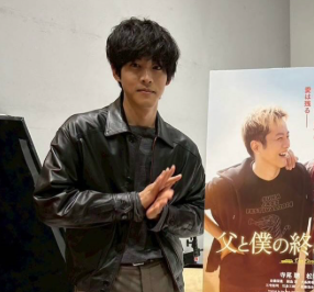 ポスターの前に立っている松坂桃李